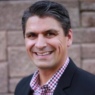 A man in a suit and tie smiling for the camera.